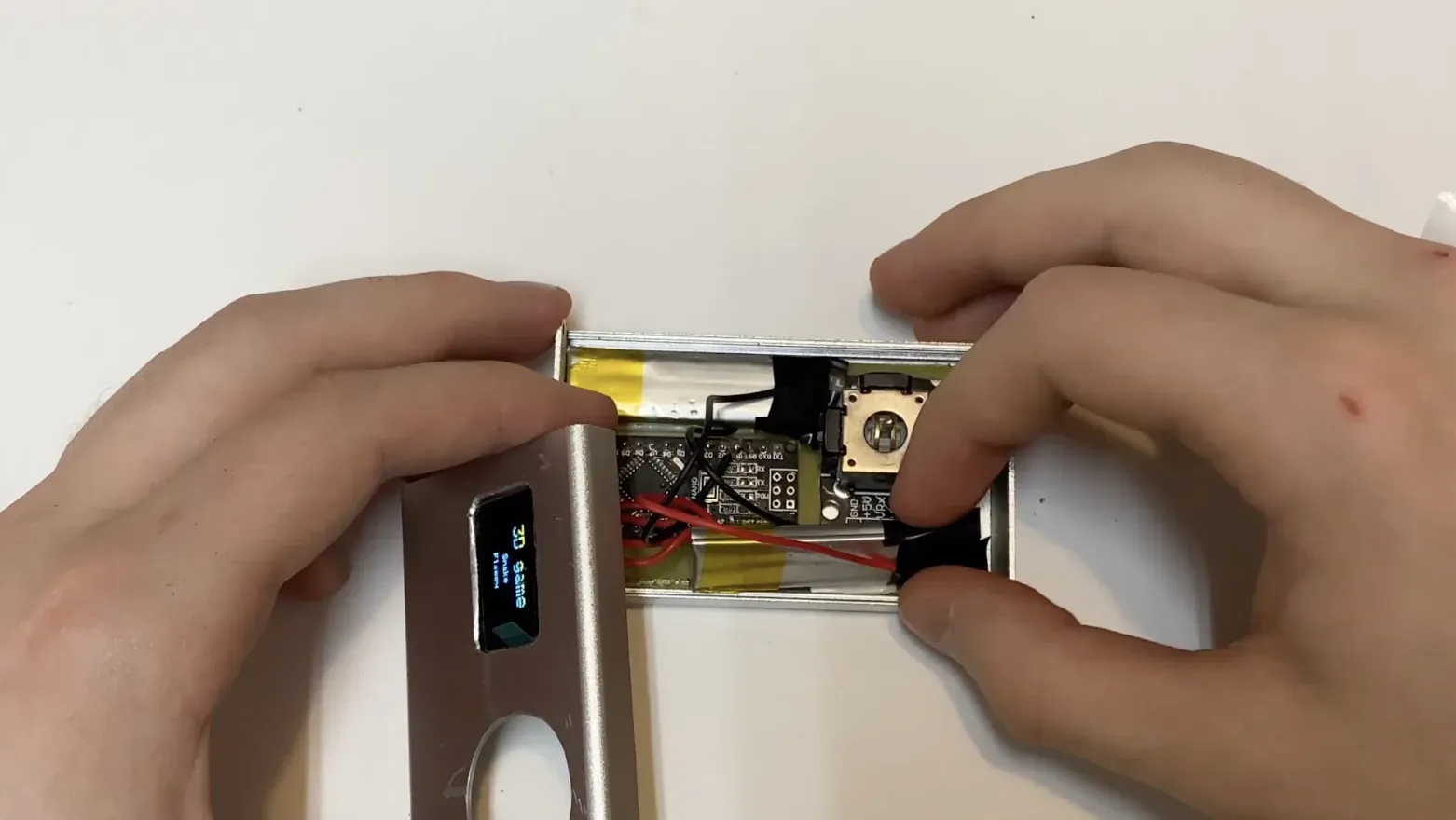 Open aluminum enclosure revealing the Arduino Nano board, joystick, wiring, and battery cells inside