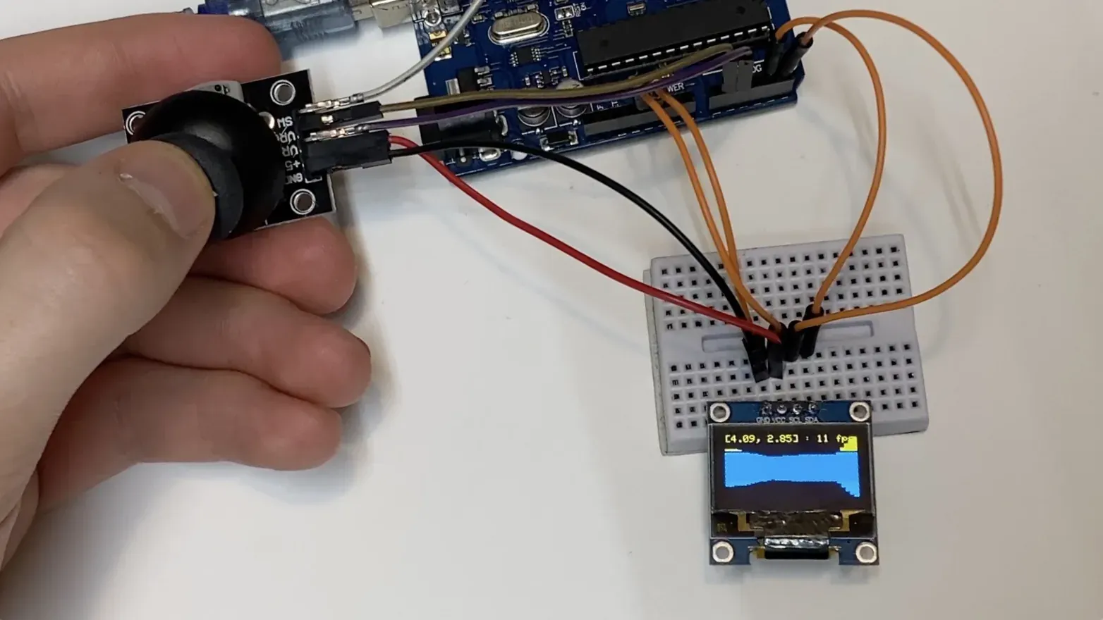 Breadboard prototype with an Arduino Uno, analog joystick, and small OLED displaying the ray-cast maze